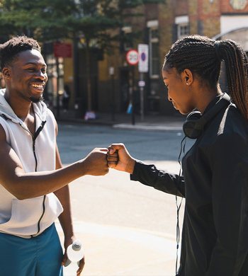 Two community members greeting each other outdoors